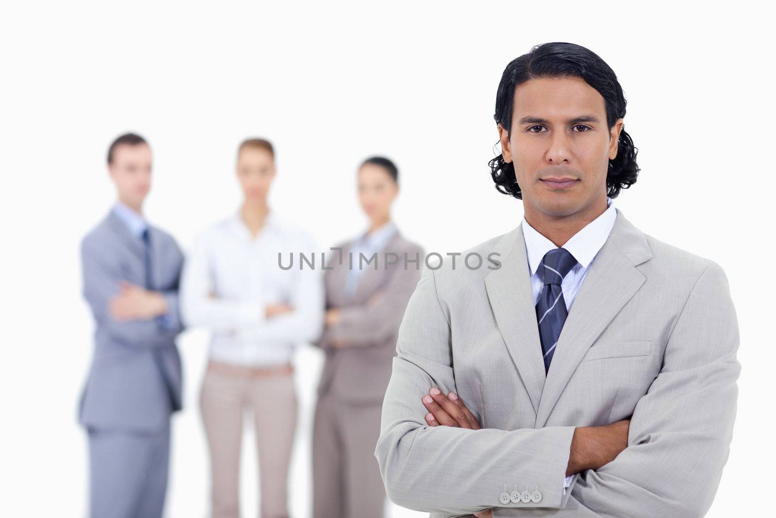 Close-up of a businessman with people in background crossing their arms against white background