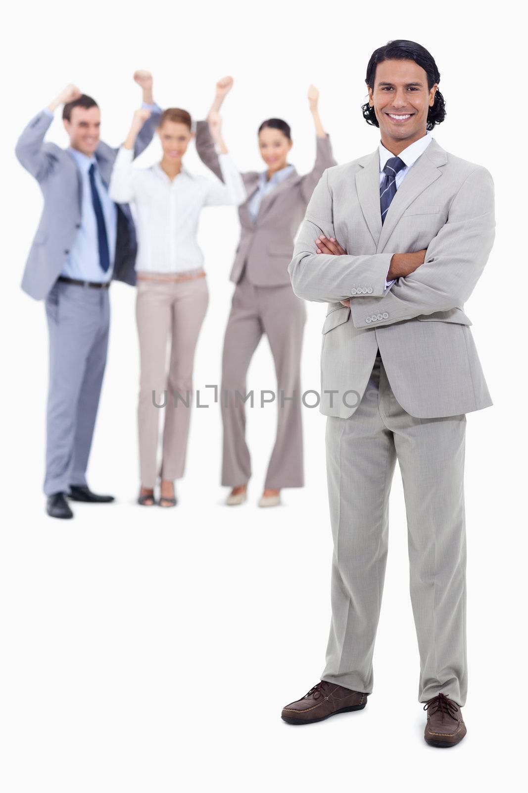 Businessman smiling and crossing his arms with cheering people behind him against white background