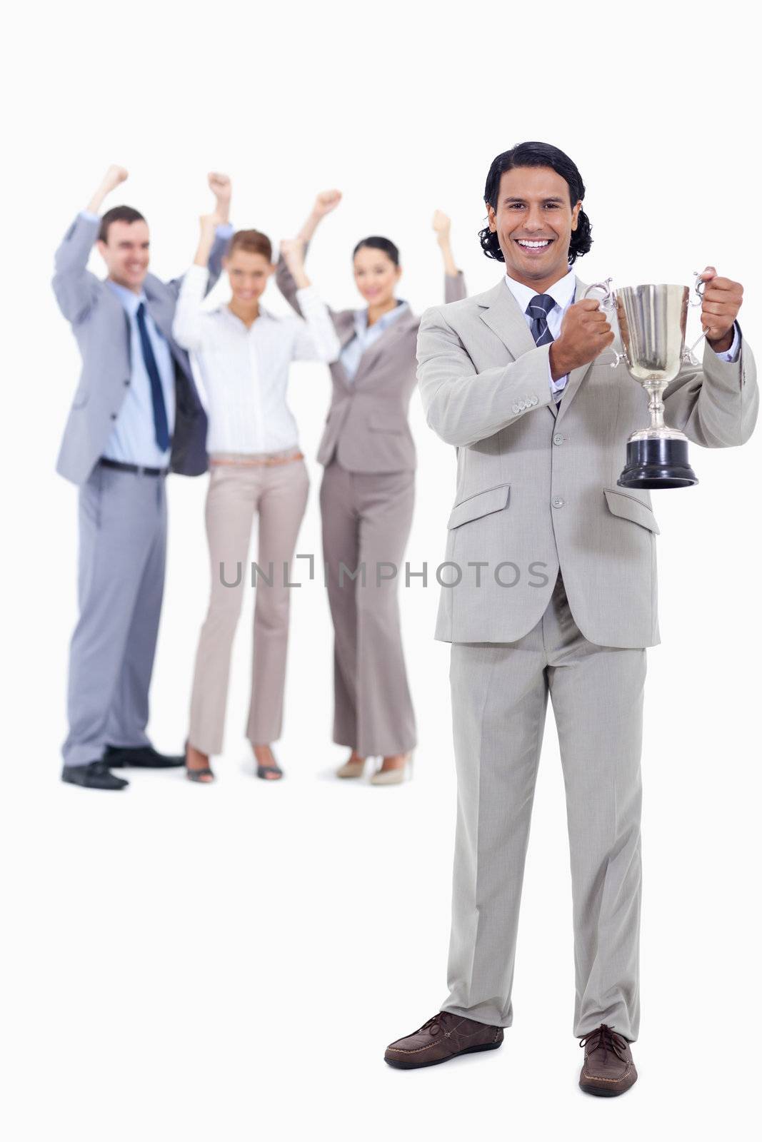 Businessman smiling and holding a cup with people cheering behind him against white background