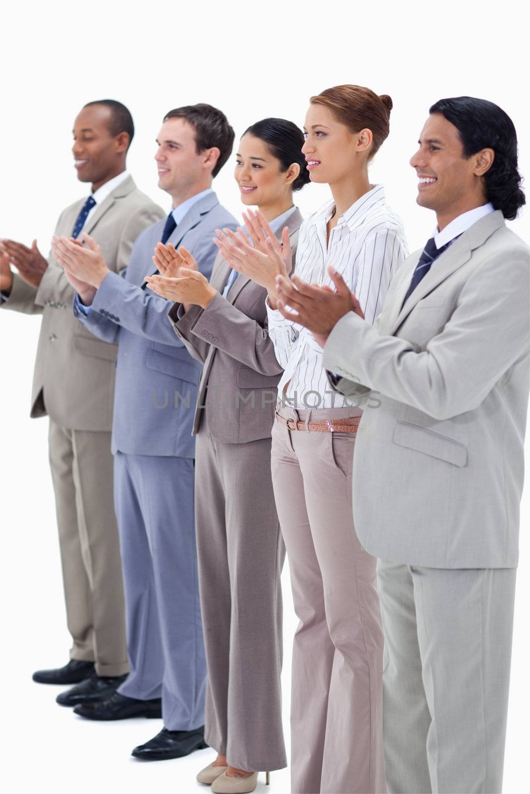 Business people smiling and applauding while looking towards the left side against white background