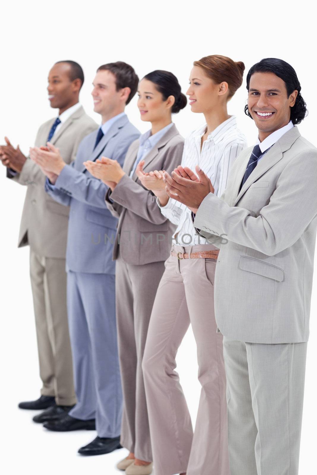 Business team smiling and applauding while looking towards the left side except for one against white background