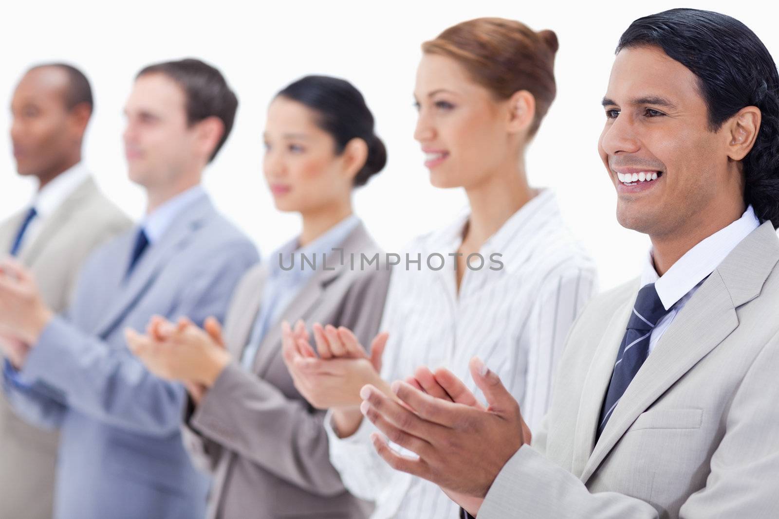 Business team applauding while looking towards the left side with focus on the first man against white background