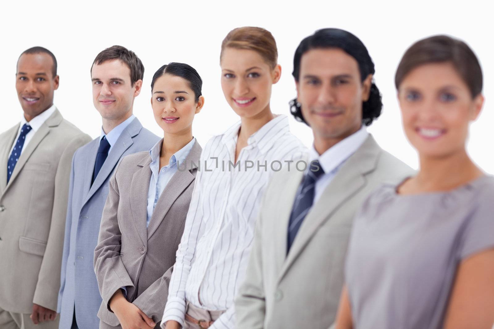 Close-up of smiling people dressed in suits looking straight with focus on the last three people