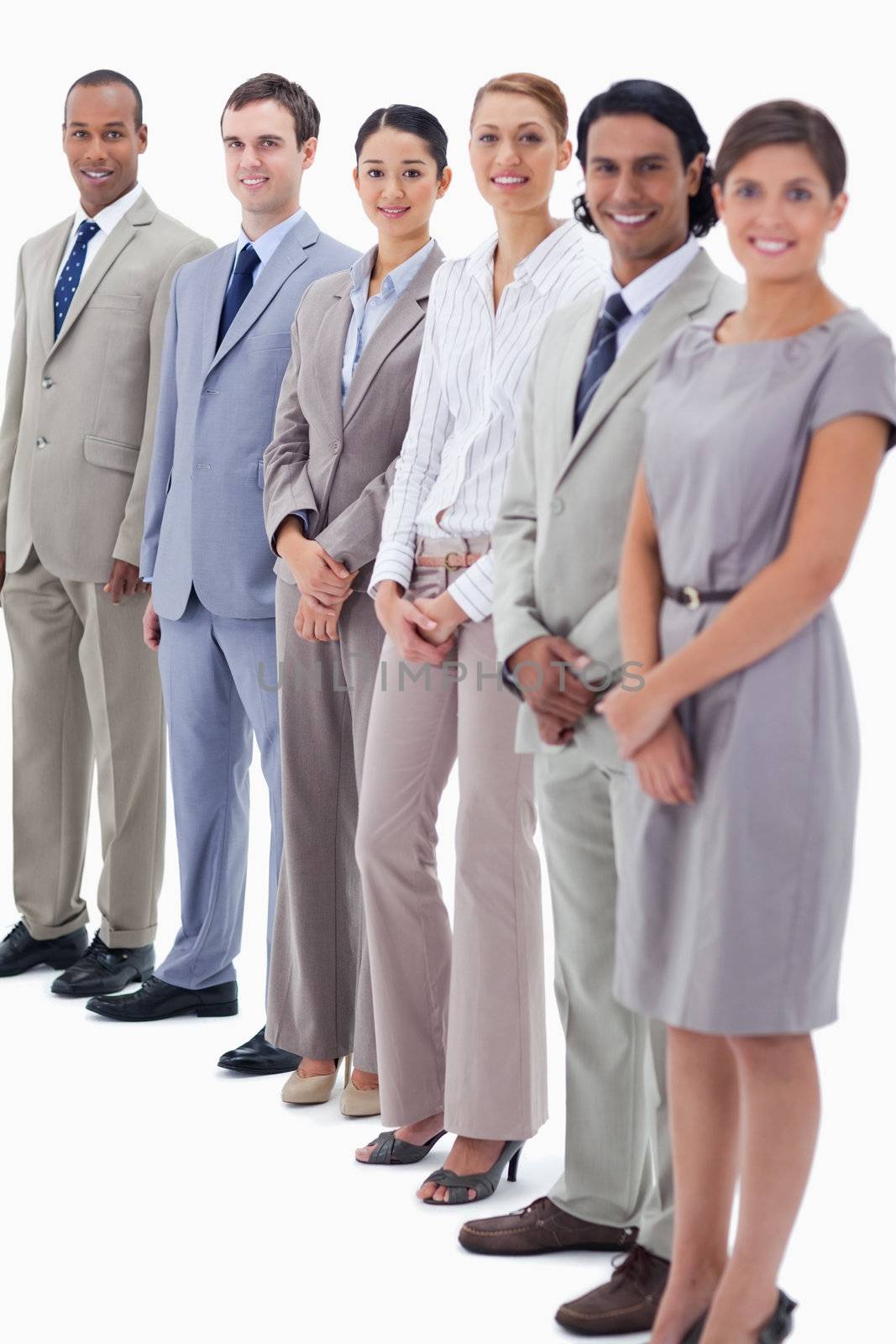 Smiling colleagues looking straight with focus on the last two people against white background