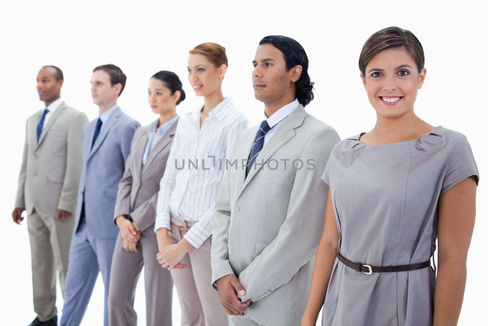 Close-up of a businesswoman smiling while looking straight and colleagues looking towards the left side against white background