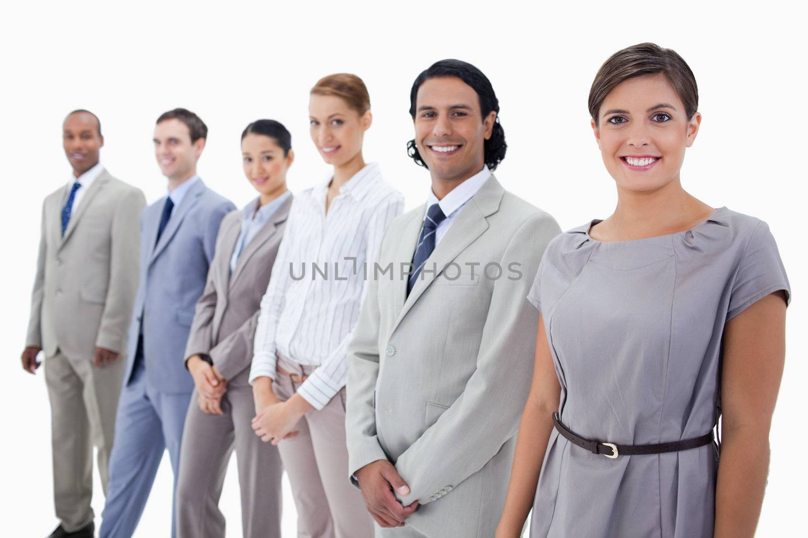 Close-up of colleagues smiling and looking straight with focus on the first two people against white background