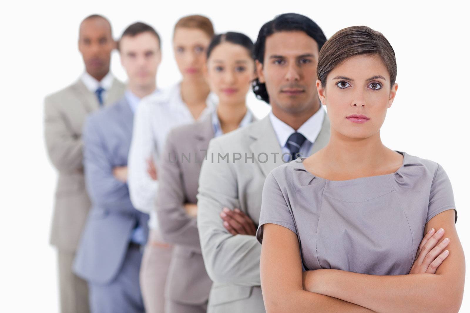Big close-up of serious workmates in single a line crossing their arms with focus on the first woman 