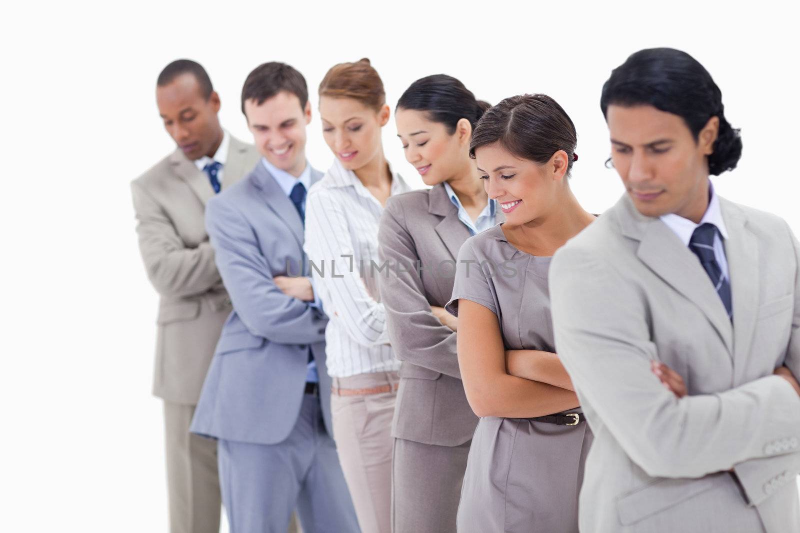 Close-up of a business team in a single line looking downwards and crossing their arms 