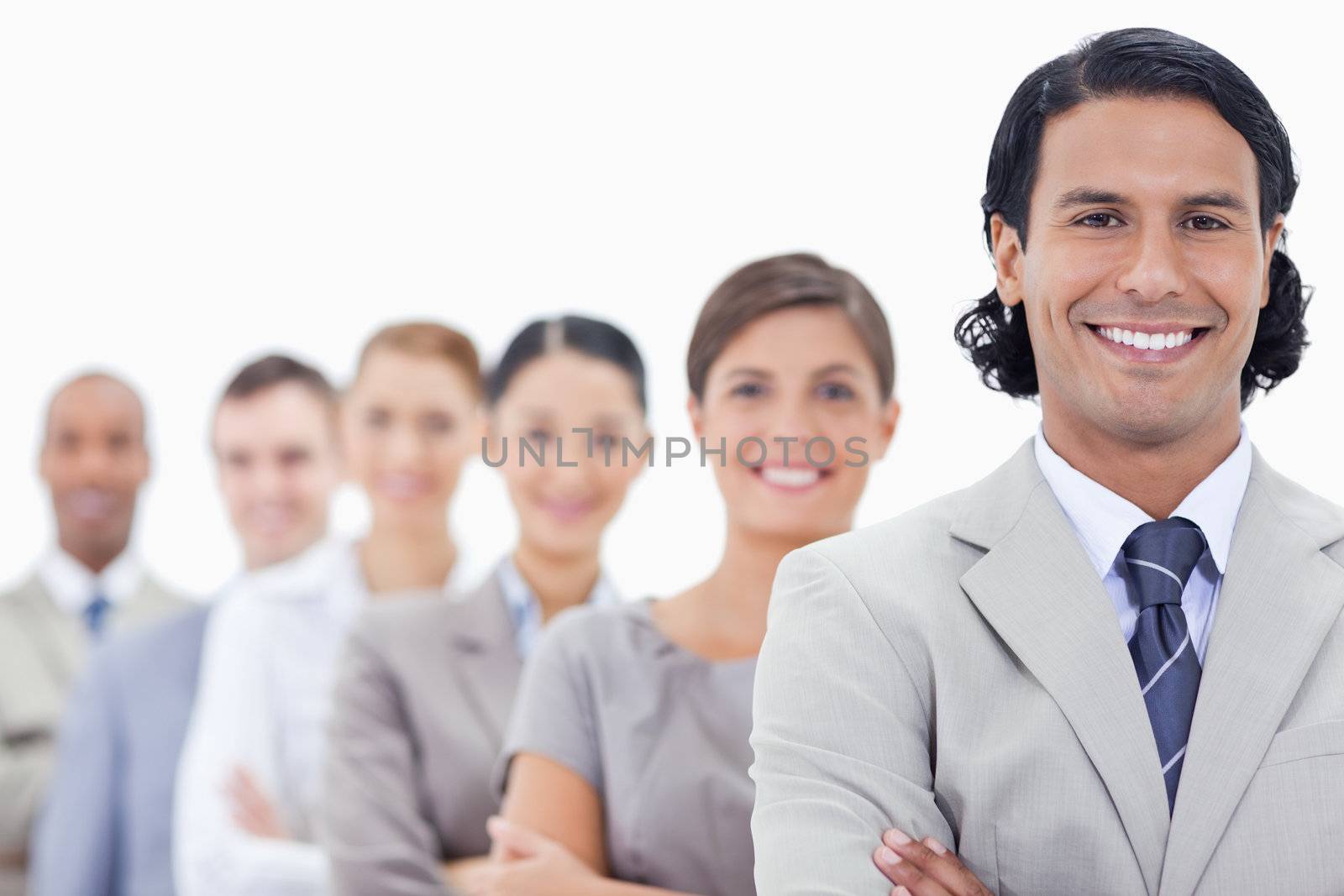 Big close-up of a happy business team crossing their arms in a single line looking straight with focus on the first man