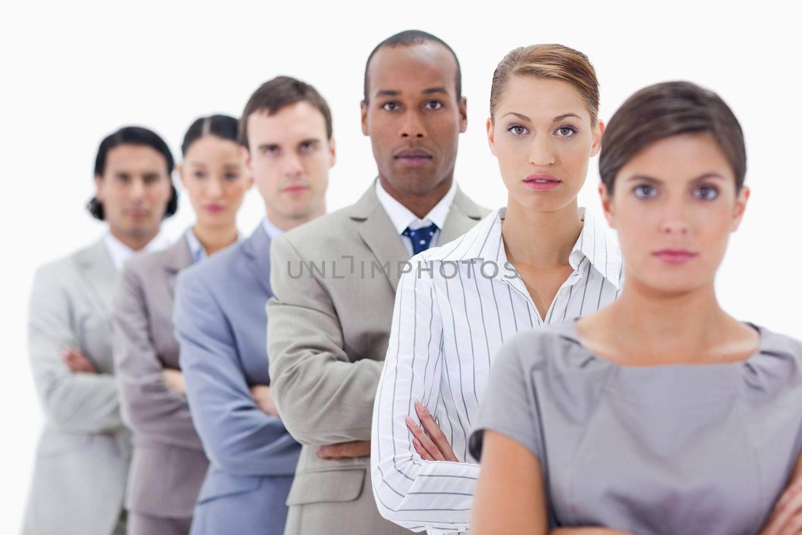 Big close-up of a serious business team in a single line crossing their arms with focus on the second woman