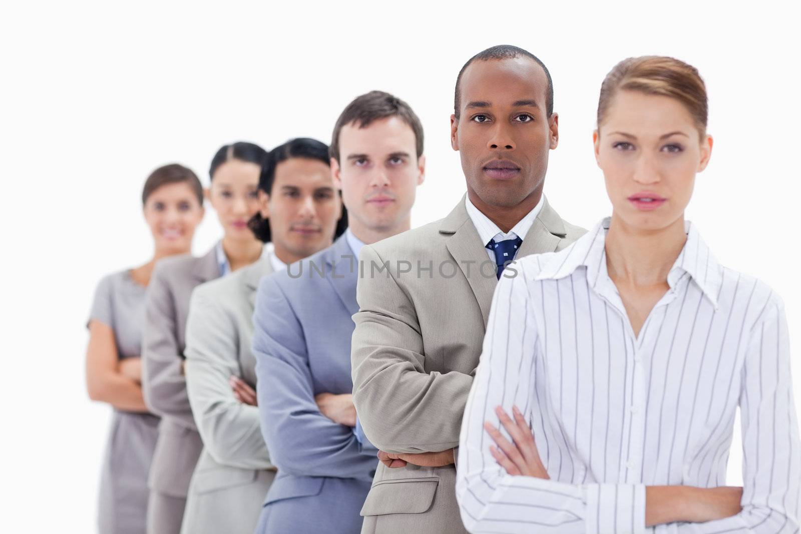 Close-up of colleagues dressed in suits crossing their arms in a single line with focus on the first man