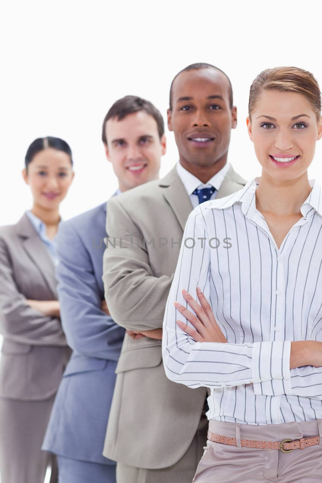 Close-up of colleagues smiling in a single line crossing their arms with focus on the first woman