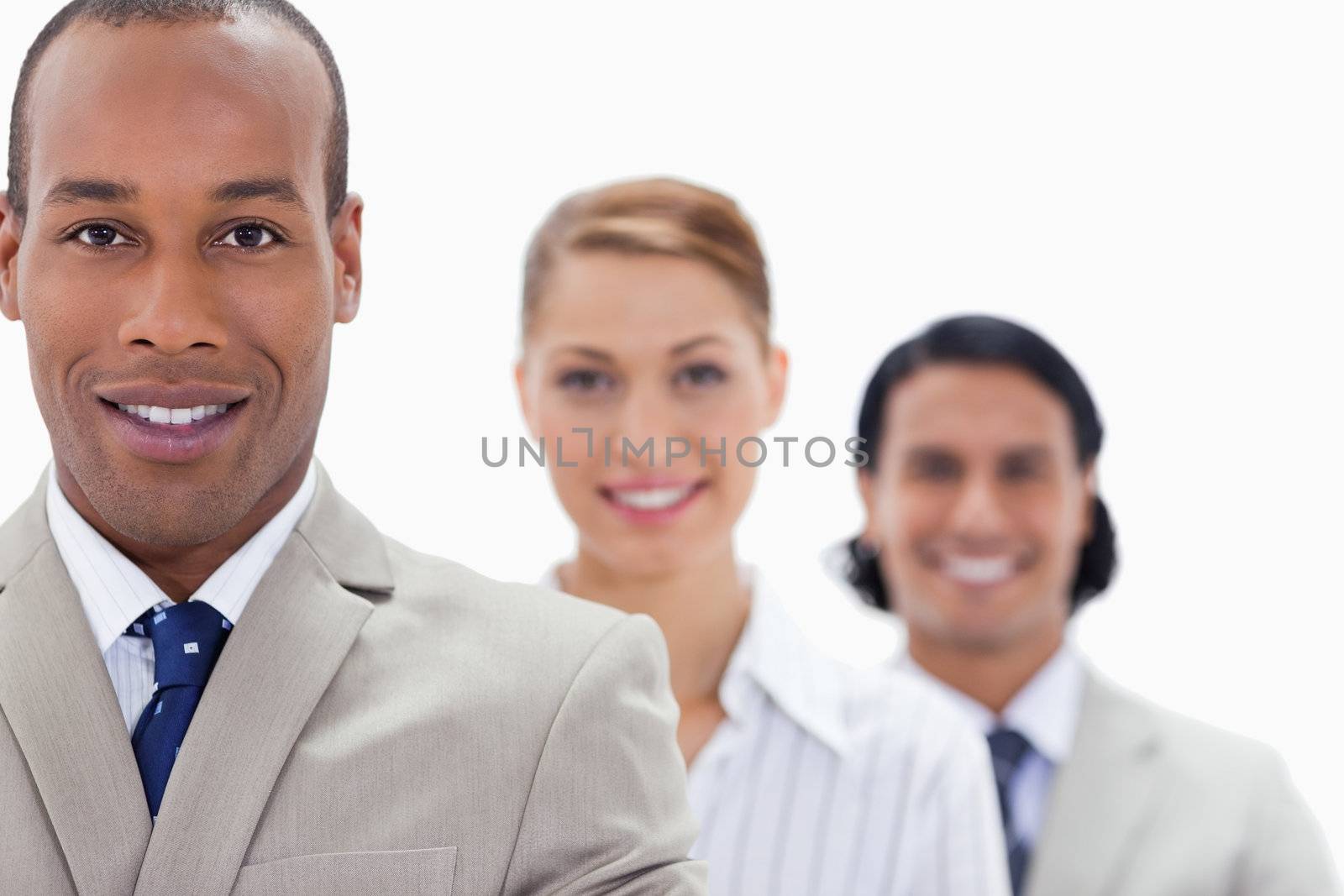 Big close-up of workmates in a single line smiling with focus on the first man