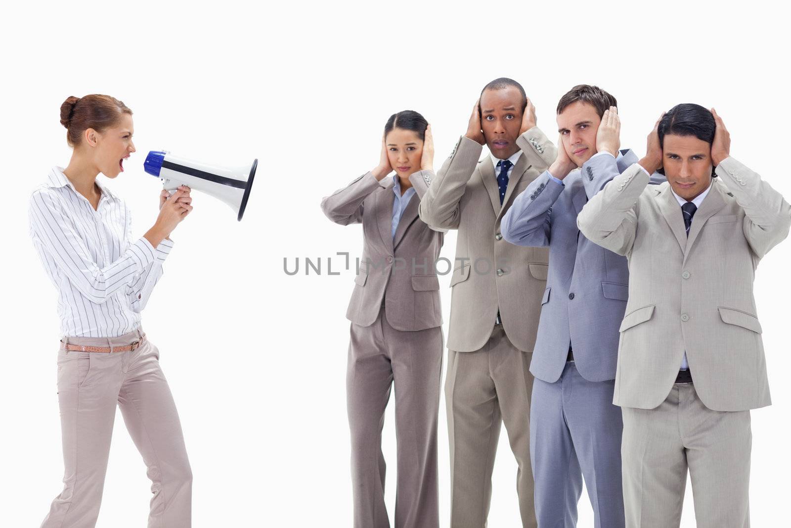 Woman yelling through a megaphone at business people with their hands on their ears against white background