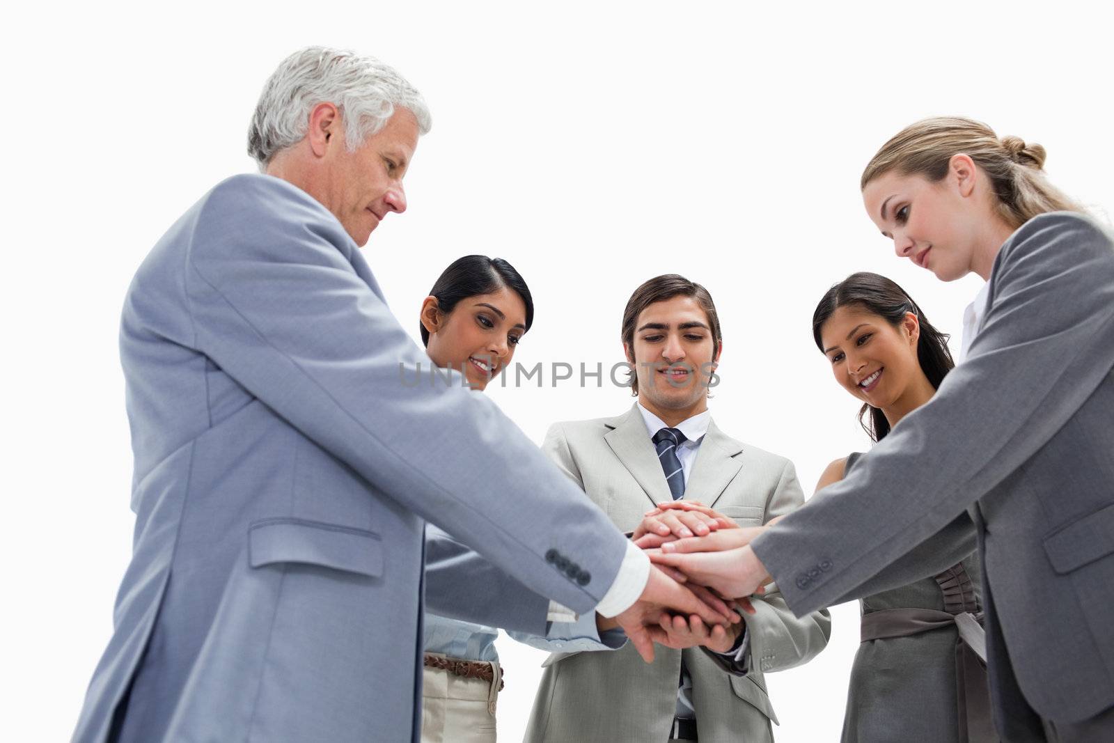 Team putting their hands on each others against white background