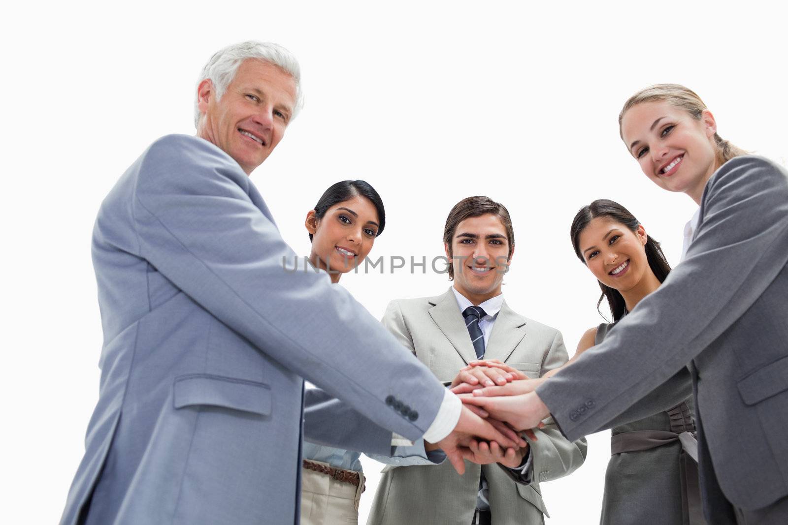 Happy team putting their hands on each others against white background