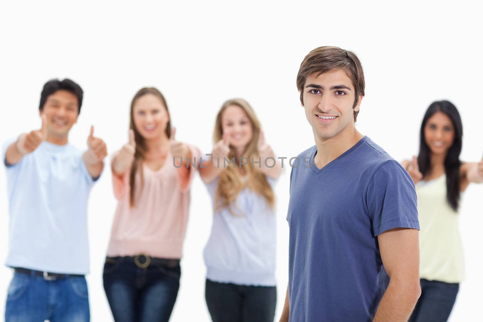 Man smiling with people approving behind him by Wavebreakmedia