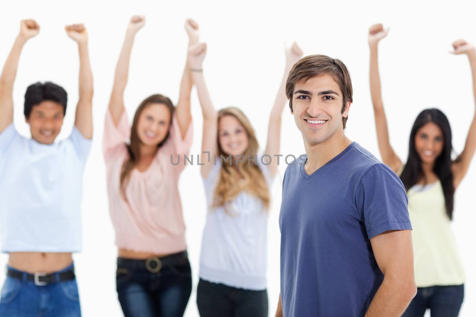 Smiling man with people behind him raising their arms by Wavebreakmedia