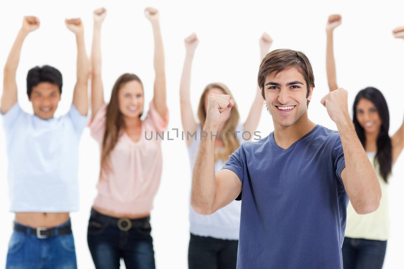 Man clenching his fists with people behind him raising their arm by Wavebreakmedia