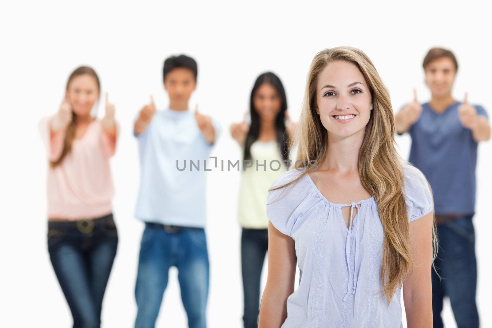 Close-up of woman smiling with people approving behind her against white background