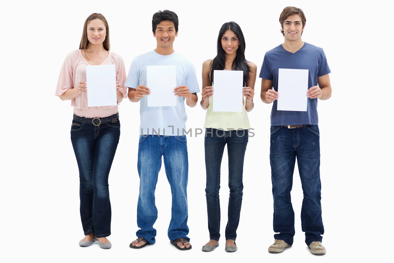 Four people in jeans holding four signs against white background