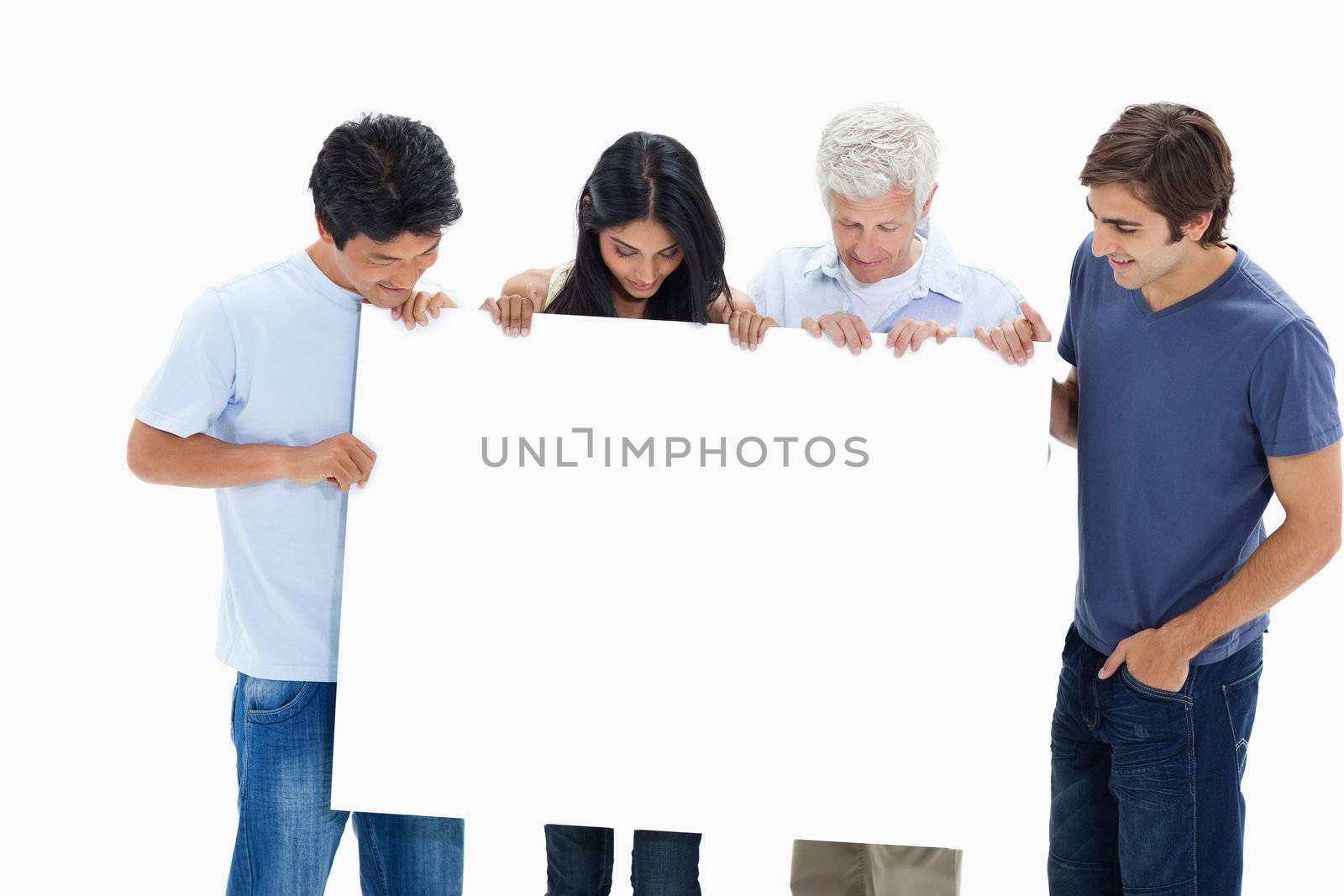 People in jeans holding and watching a big sign against white background