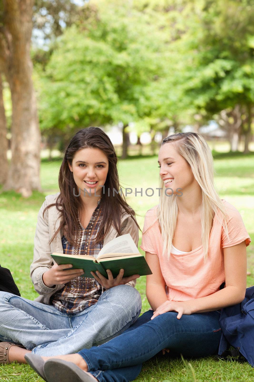 Two teenagers sitting with a textbook by Wavebreakmedia