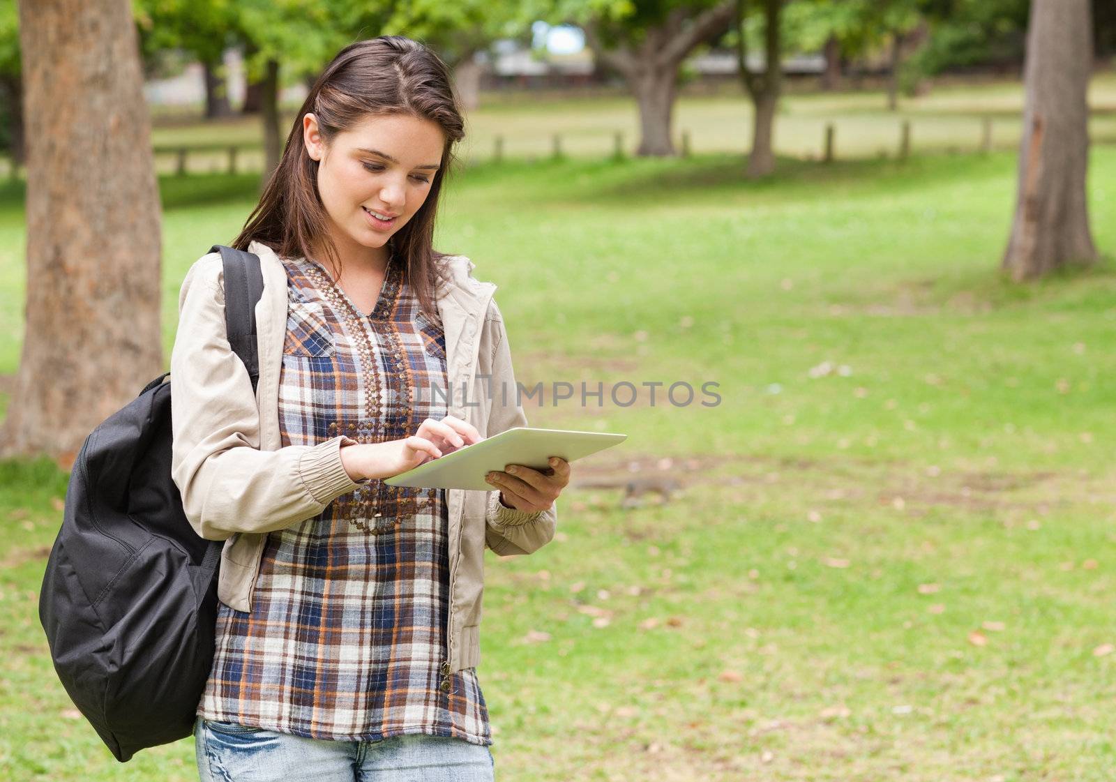 Young female student using a tactile tablet in a park