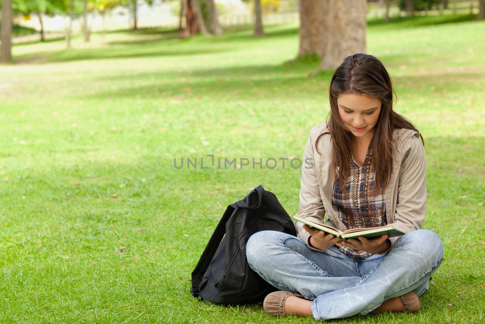 Teenager sitting while reading her textbook in a park