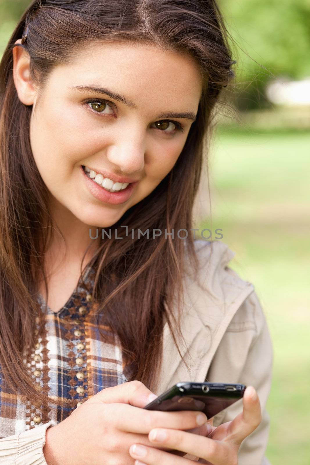 Portrait of a cute teenager using a smartphone in a park