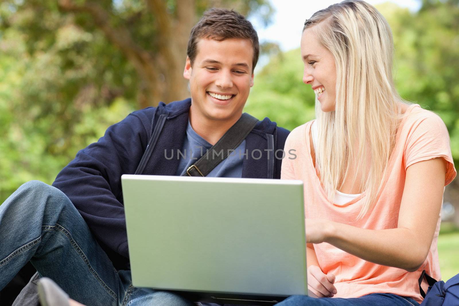 Laughing young people sitting while using a laptop by Wavebreakmedia