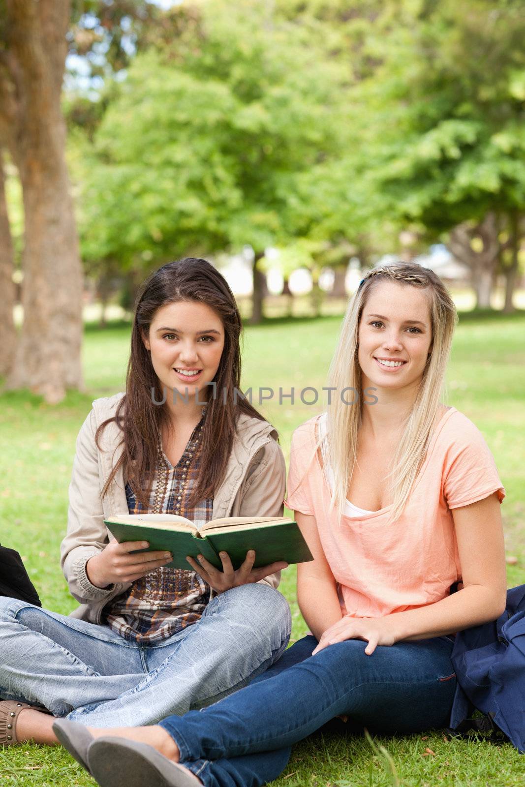 Portrait of female teenagers sitting with a textbook by Wavebreakmedia