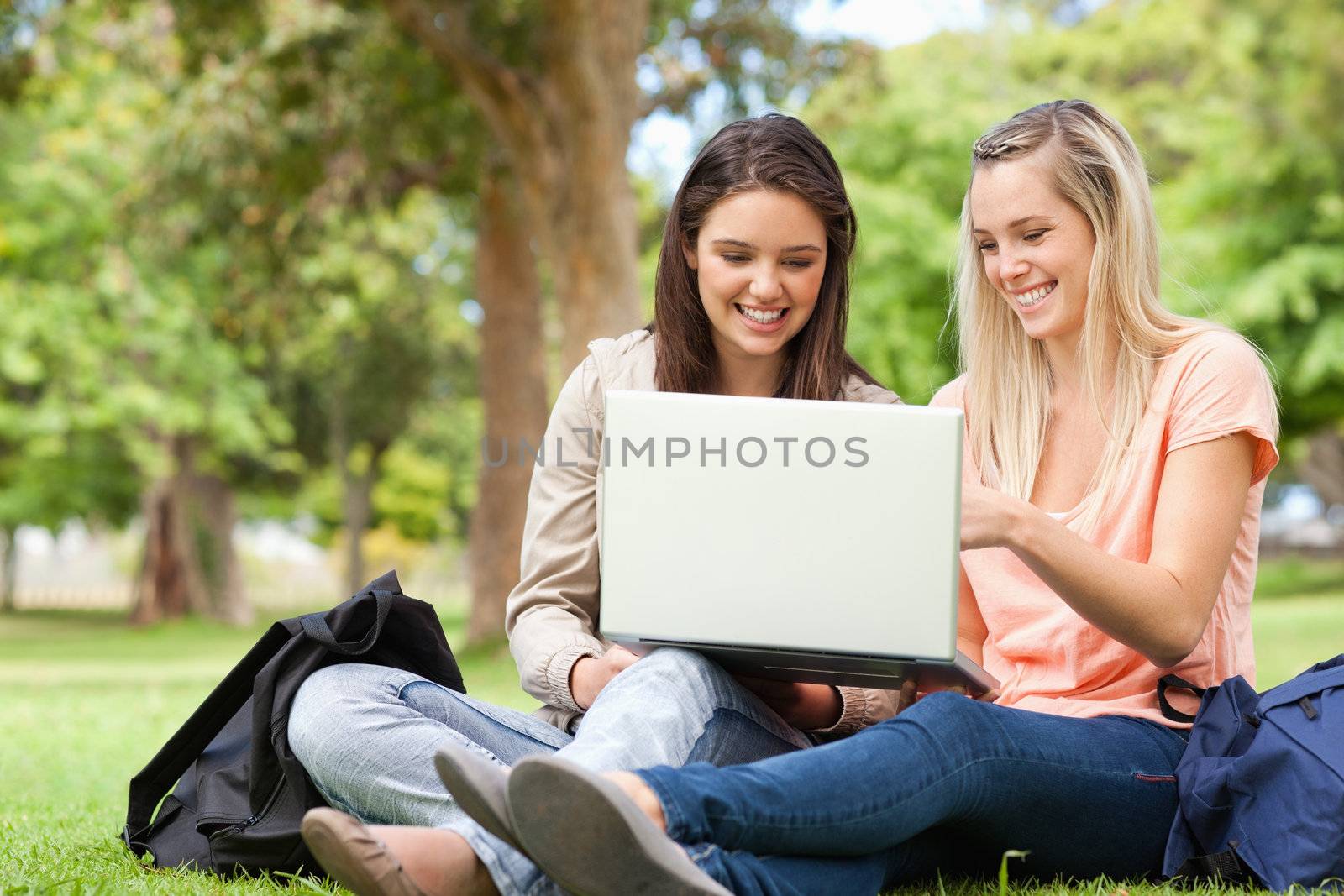 Laughing teenagers sitting while using a laptop by Wavebreakmedia