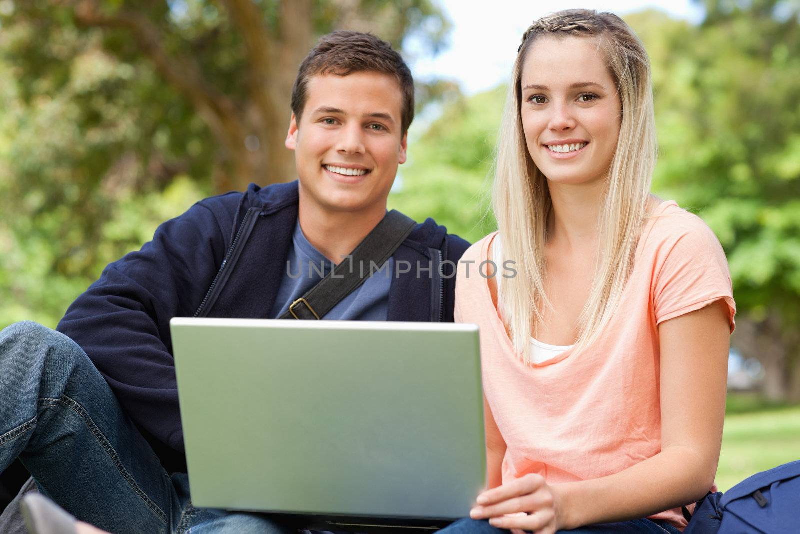 Portrait of two students laughing while sitting with a laptop by Wavebreakmedia