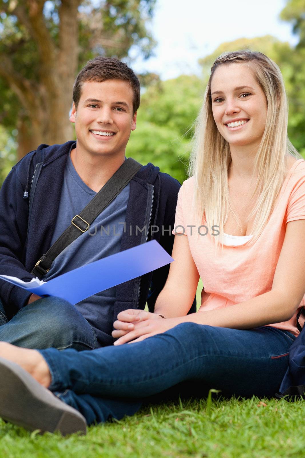 Portrait of a smiling tutor helping a teenager to revise in a park