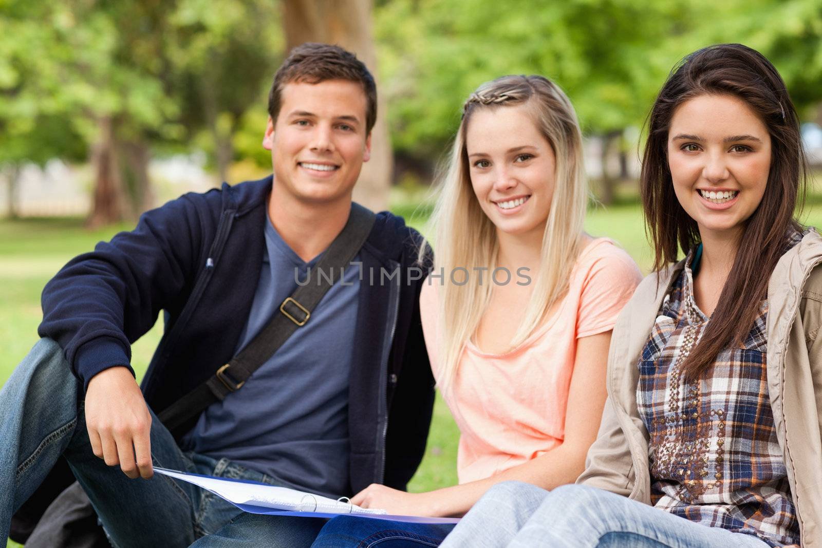 Portrait of students studying together while sitting in a park