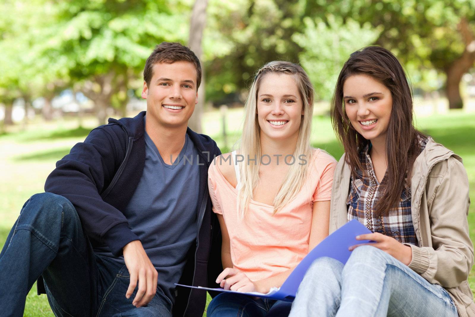 Portrait of three teenagers studying together in a park