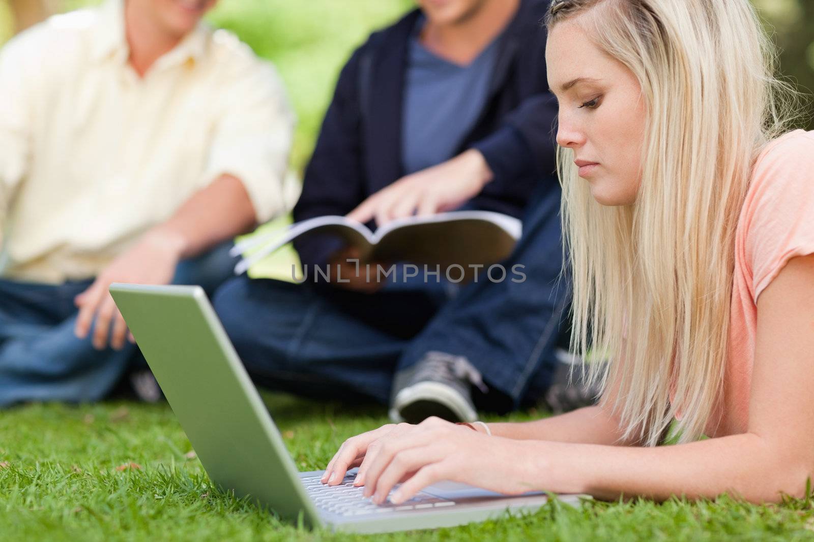 Close-up of a girl using a netbook while lying in a park by Wavebreakmedia
