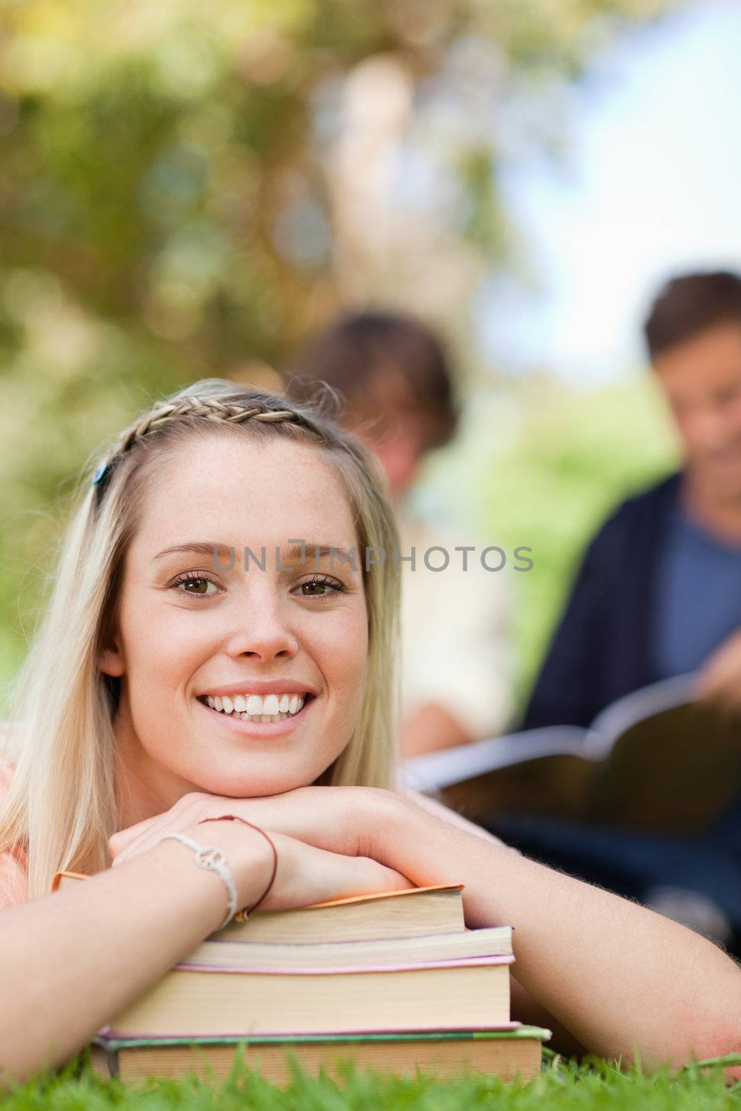 Close-up of a girl lying head on her books in a park by Wavebreakmedia