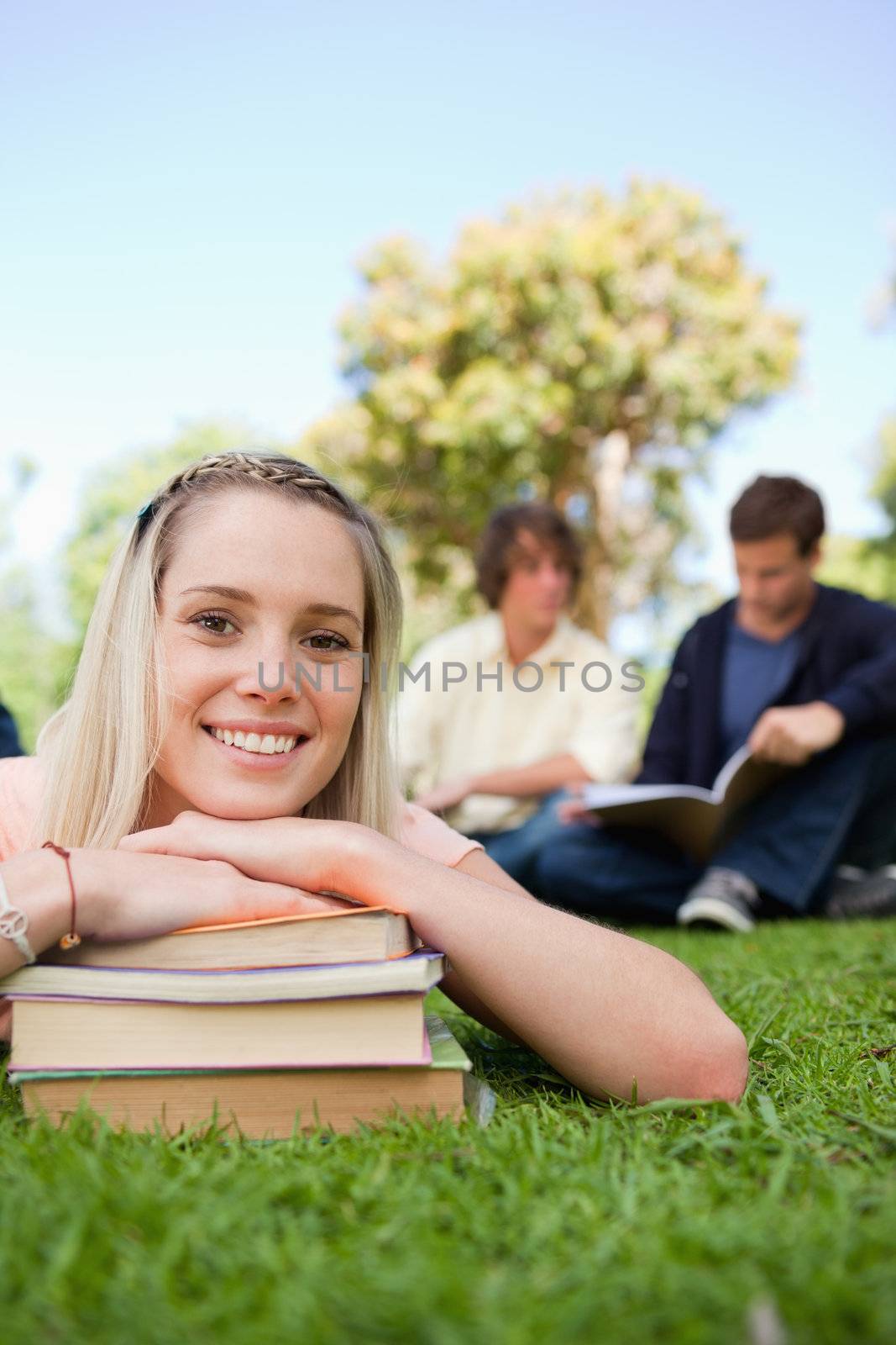 Close-up of a girl lying head on her books in a park by Wavebreakmedia