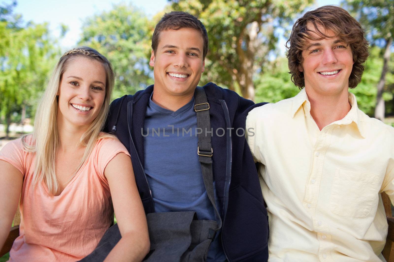 Portrait of three smiling students in a park together