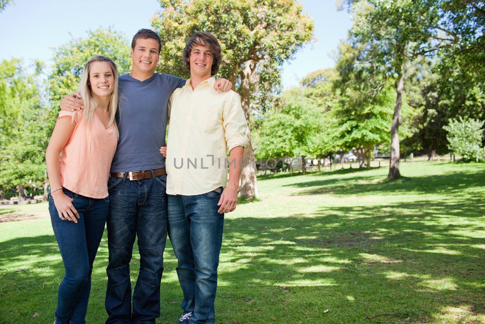 Portrait of three smiling students shoulder to shoulder by Wavebreakmedia