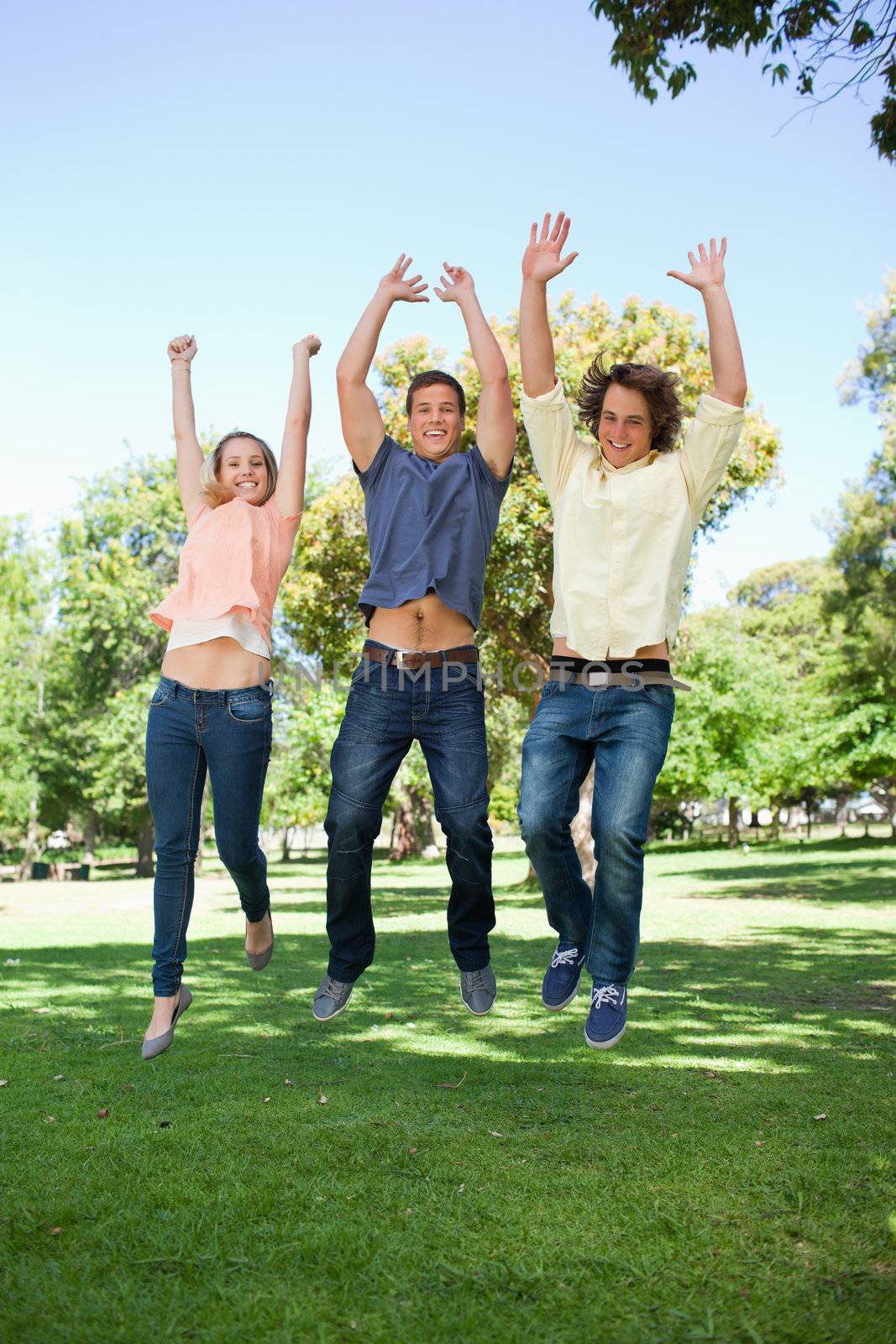 Three students jumping in a park