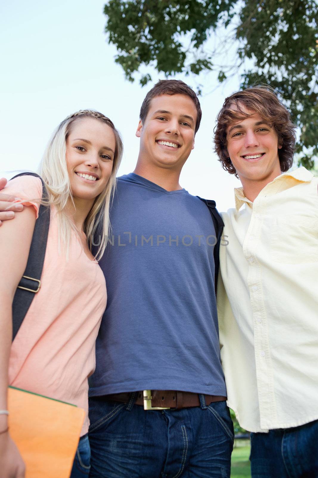 Low angle-shot of three friends shoulder to shoulder in a park