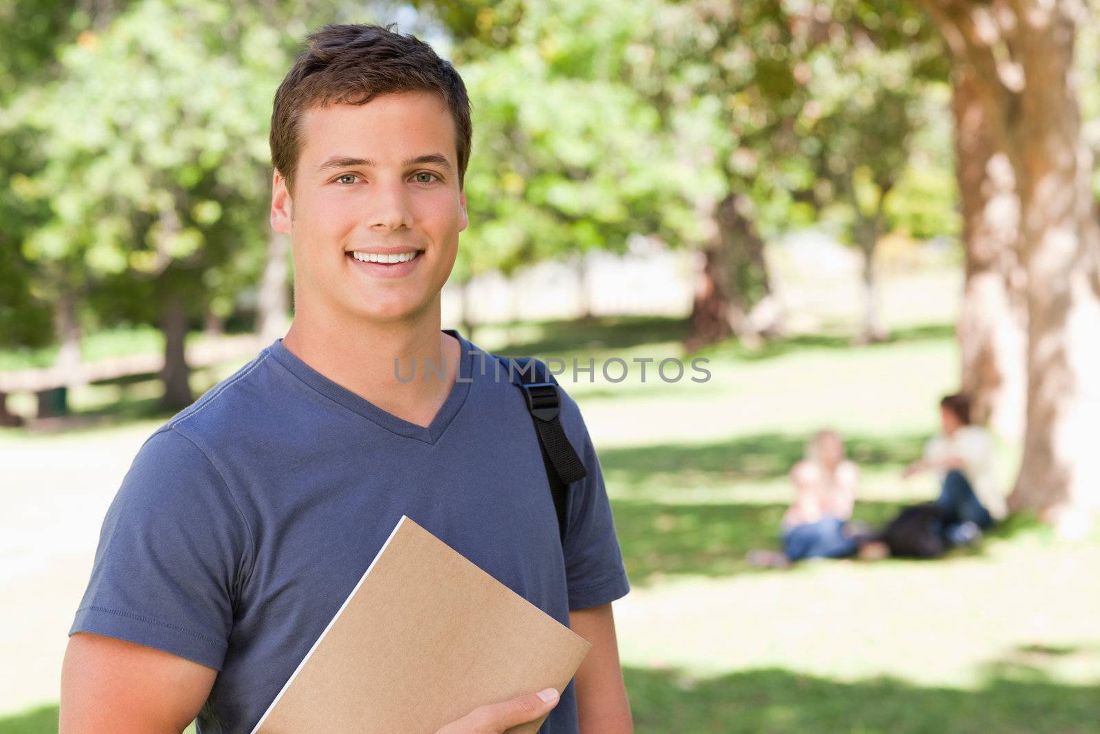 Portrait of a student smiling while holding a textbook by Wavebreakmedia