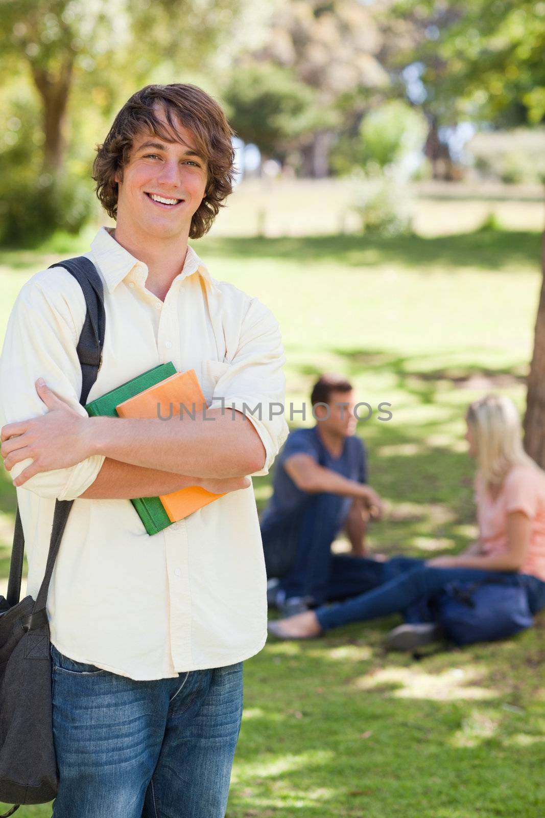 Smiling young man posing with textbook by Wavebreakmedia