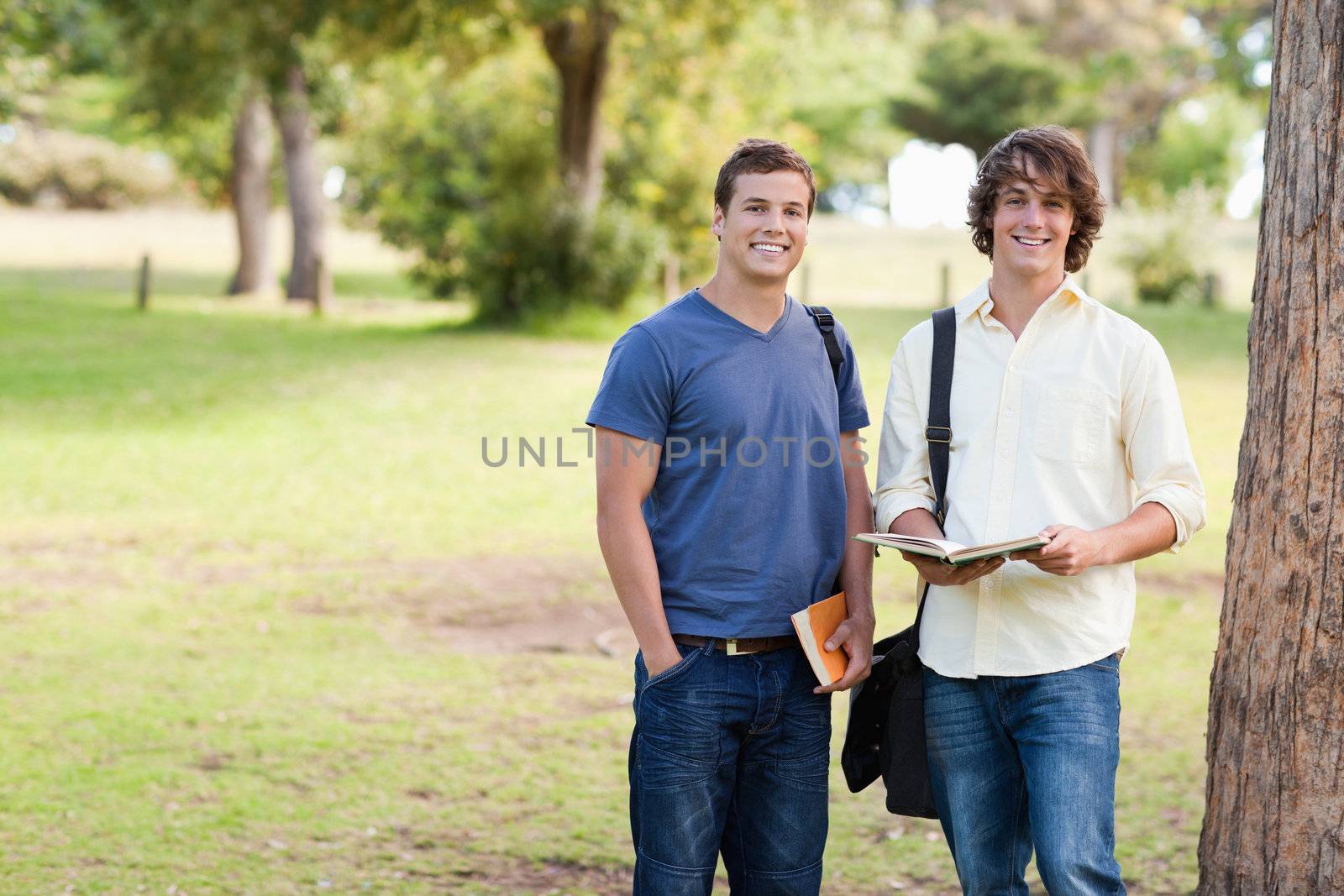 Portrait of two standing male students talking in a park