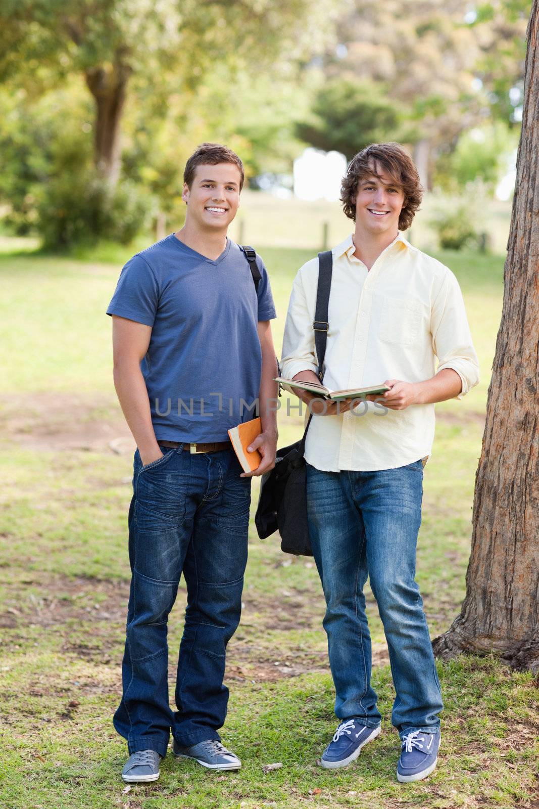 Portrait of two smiling male students posing in a park