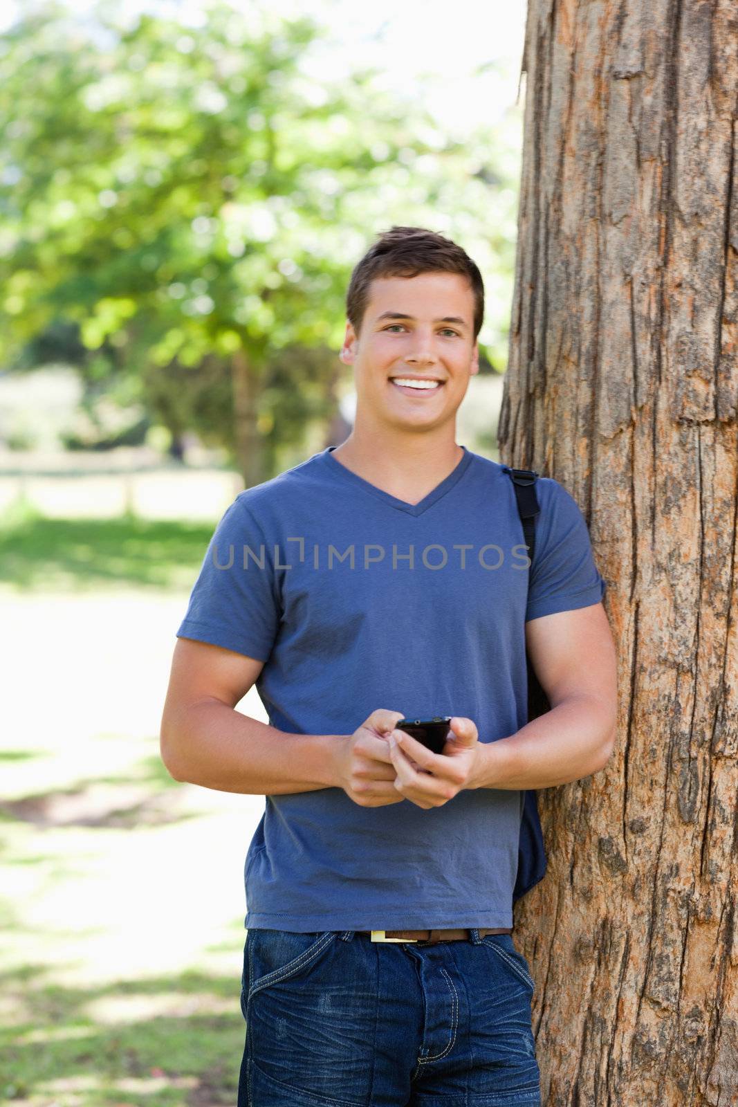 Portrait of a muscled young man using a smartphone in a park