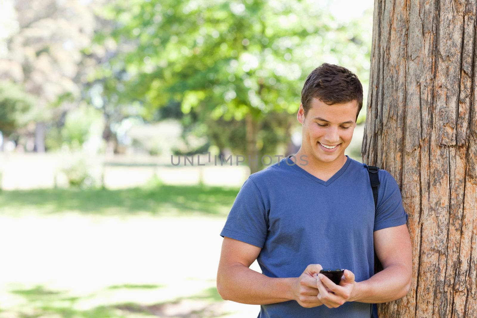 Muscled student using a smartphone in a park